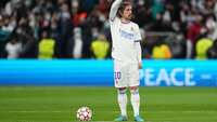 Luka Modrić im weißen Trikot bereitet sich auf einen Freistoß im Stadion vor.