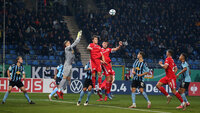 Torwart und Spieler kämpfen um den Ball bei einer Ecke im Fußballstadion während eines Pokalspiels.